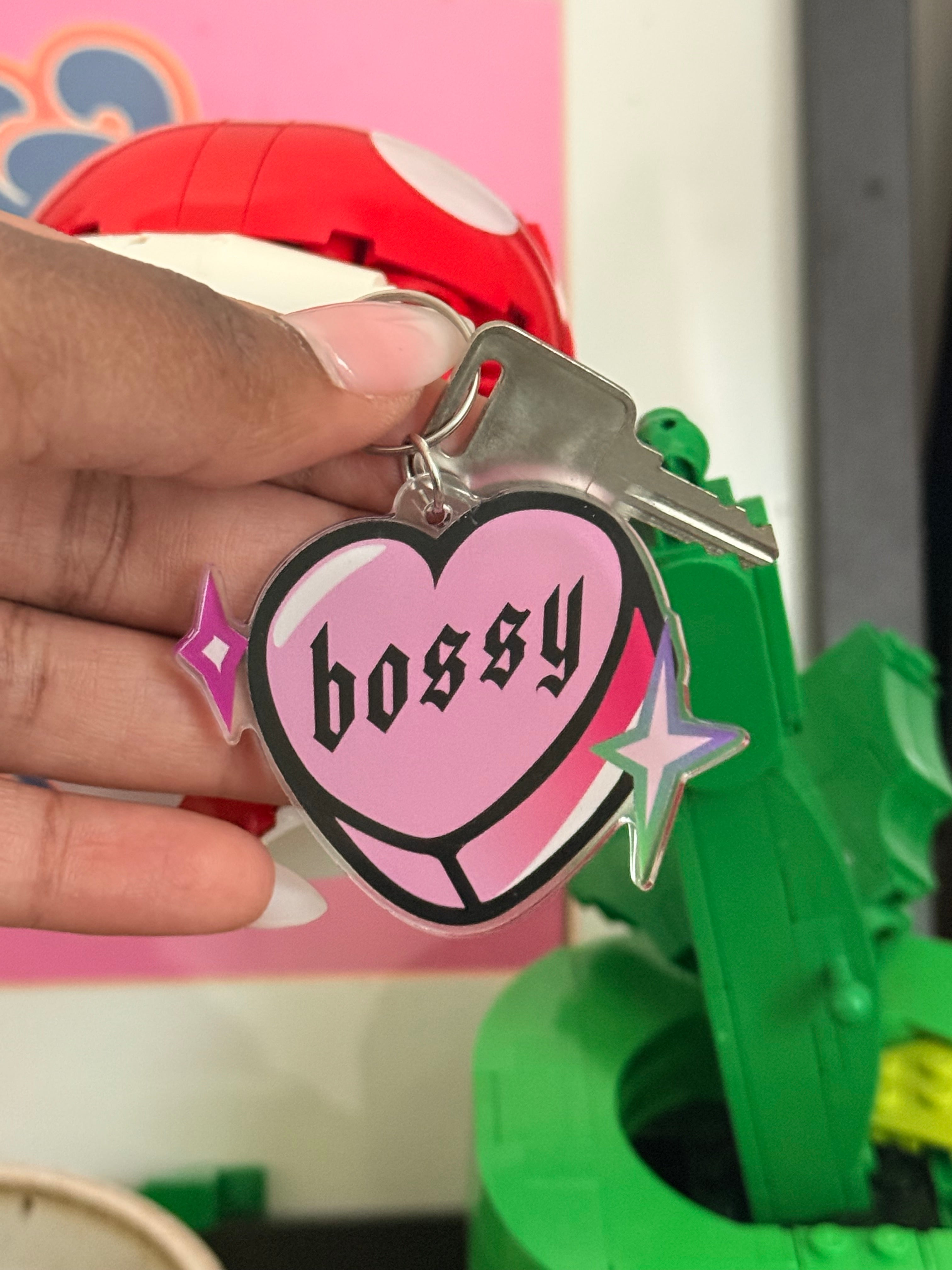 Keychain with a pink heart design held by a hand, with colorful background